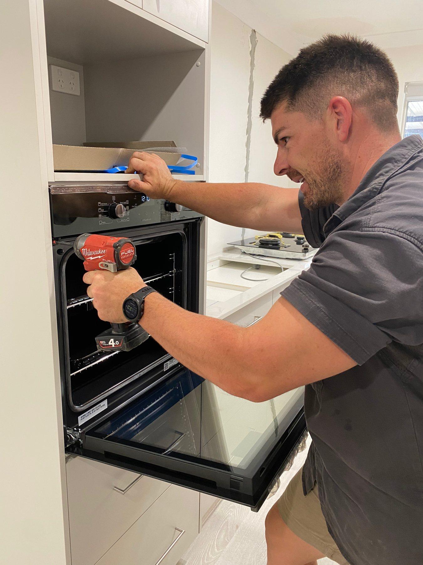 Quantum electrician installing and connecting a wall oven in a new kitchen